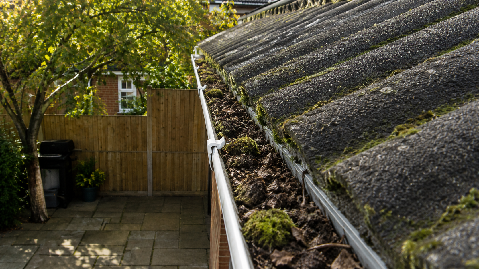 Gutter section showing concentrated debris accumulation before cleaning — illustrating how wind funnels debris into corners and valleys